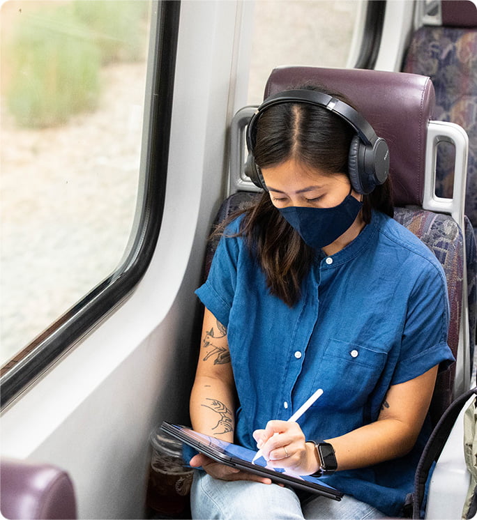 A Metrolink train rider words on a digital tablet device while traveling.