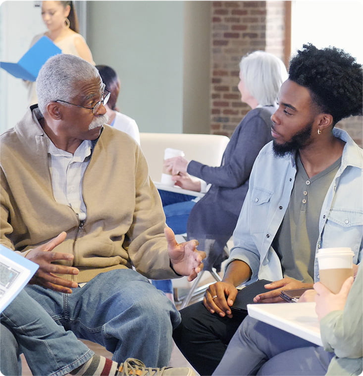 A young man and senior man sitting and discussing topics.