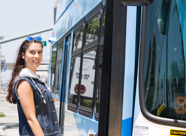 A young woman smiles before boarding a bus